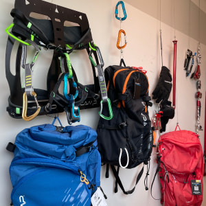 Gurte, Taschen und weitere Kletterausrüstung hängt an einer Wand.