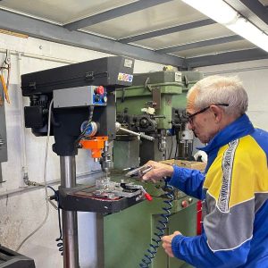 Ein Mann steht an einer Maschine, die gerade einen Karabiner von Camp herstellt.