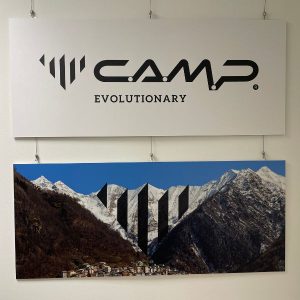 Das C.A.M.P. Logo ist zu sehen. Darunter hängt ein Bild, auf dem die Bergspitzen des Heimatbildes das Logo abbilden.