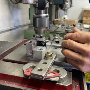 Eine Hand führt eine Maschine, die einen Karabiner herstellt.