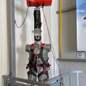Ein Torso mit einem roten Klettergurt an hängt an einer Messvorrichtung im Fallturm.