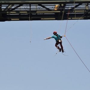 Ein Kletterer hängt unter einer Brücke im Seil und Gurt.