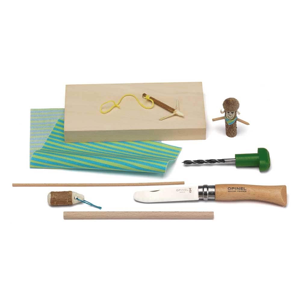 Kosmos Schnitz Set mit Holzblock, blau-grün gestreiftem Stoff, Opinel Kinderschnitzmesser mit Holzgriff, Bohrer mit grünem Griff, Holzstäben und kleinen Holzfiguren