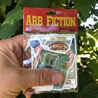 Hand hält ARB Fiction Pack Vol. 7 Sticker Pack mit mehreren Aufklebern, darunter ein Baumkletterer und ein Charakter mit Helm, Hersteller ARB Fiction