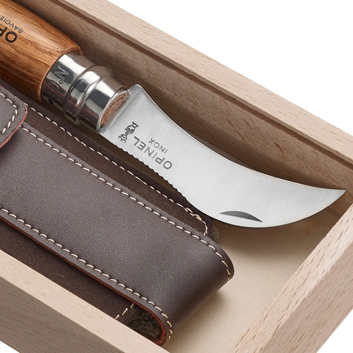 Nahaufnahme des gebogenen Messers mit der Gravur "OPINEL INOX" und des Lederetuis in der hellen Holzschachtel