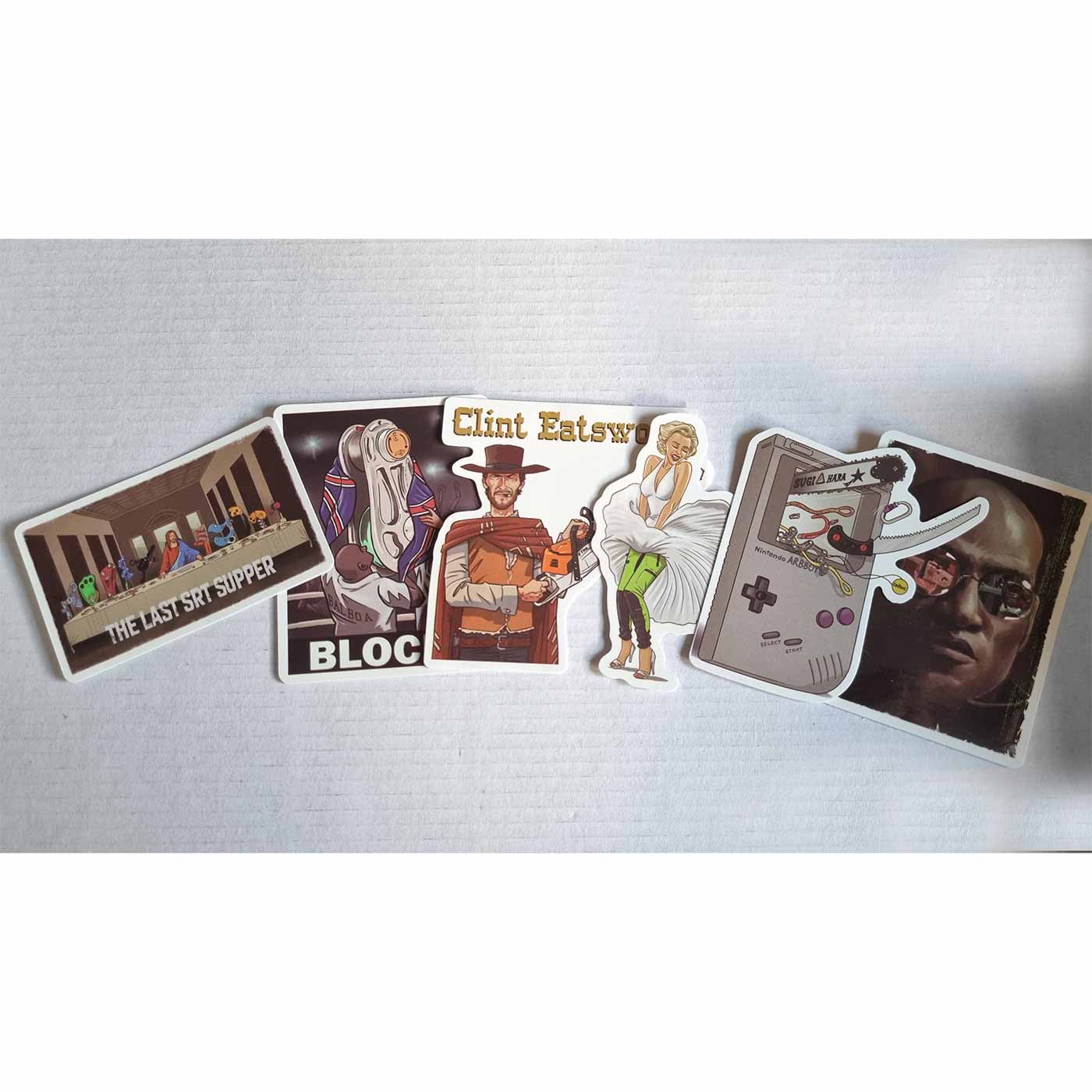 Sechs einzelne Aufkleber aus dem ARB Fiction Pack Vol. 2, darunter "THE LAST SRT SUPPER" mit Figuren an einem Tisch, "BLOCKY" mit einer Figur in weißem Gewand, Clint Eatswood mit Kettensäge, Frau mit weißem Kleid und grünen Hosen, Gameboy-ähnliches Gerät 