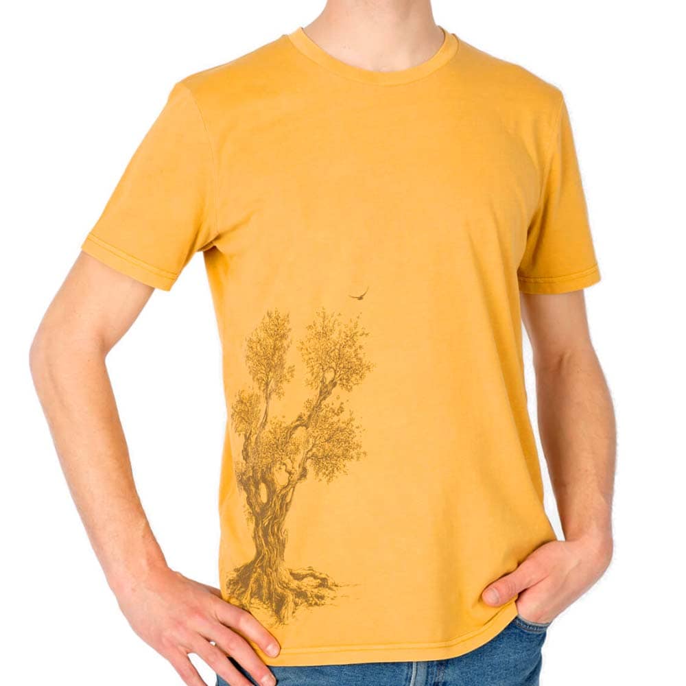 Olive Tree T-Shirt, Nahaufnahme eines gelben T-Shirts mit braunem Olivenbaumdruck, getragen von einem Mann mit einer Hand in der Hosentasche
