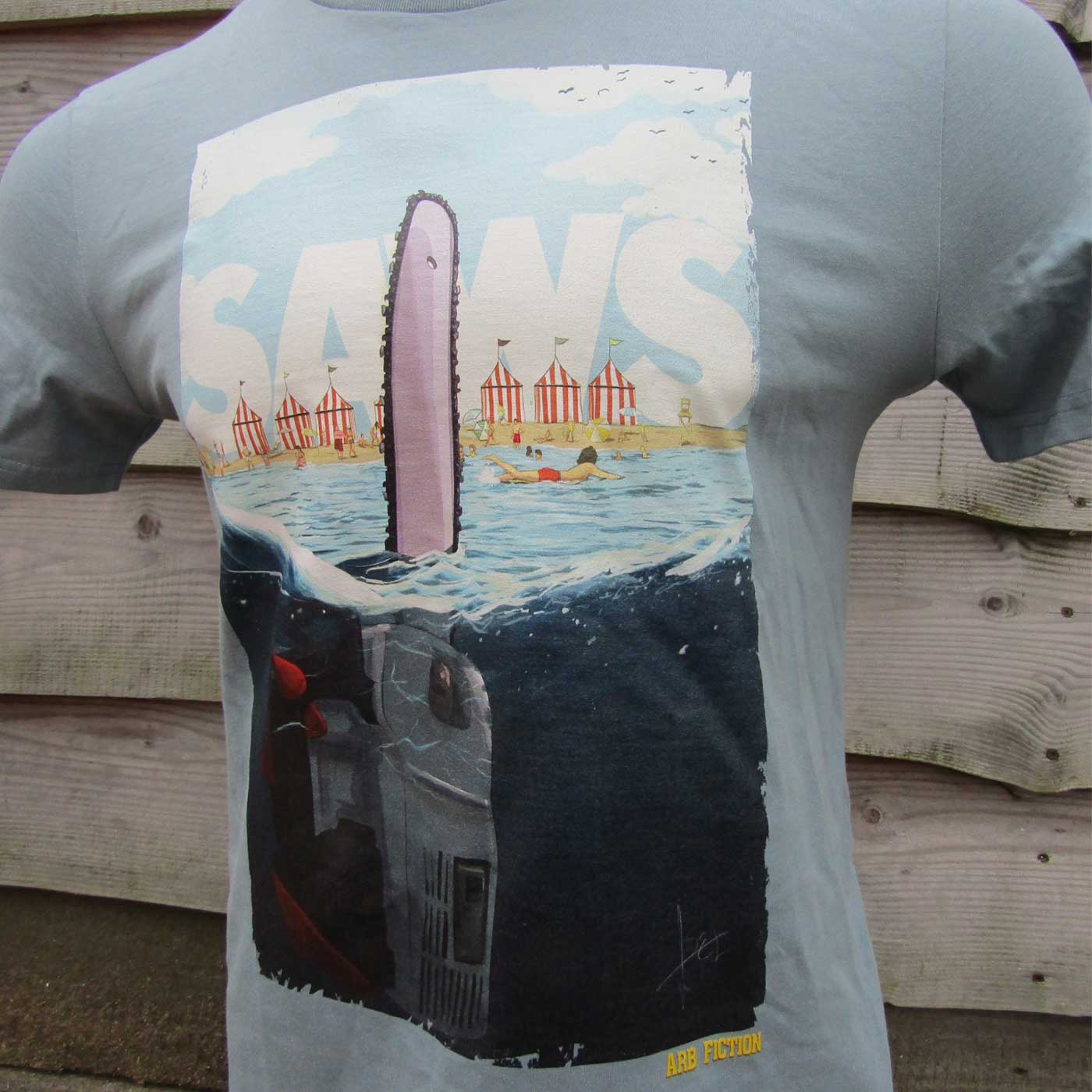 Graues T-Shirt mit einem großen Aufdruck eines freischwebenden Kettensägens im Wasser, darüber der Schriftzug „SAWS“ und im unteren Bereich der Text „ARB FICTION“.