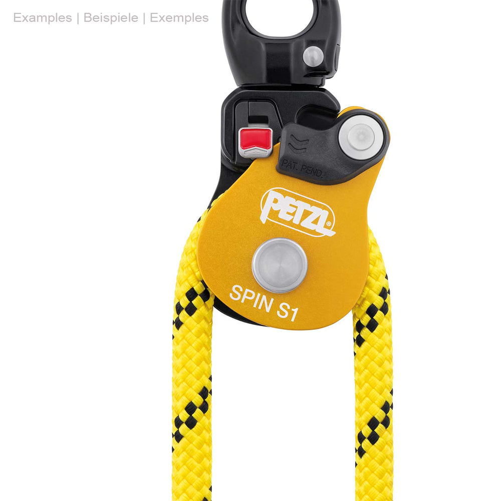 Petzl Spin S1, gelb-schwarze Umlenkrolle mit Metallring oben und gelbem Seil durchgezogen, roter Knopf auf schwarzem Teil sichtbar
