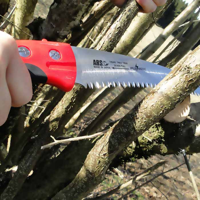 CTR-32 Pro Säge von ARS in Gebrauch, schneidet einen Ast, sichtbares gezahntes Blatt und roter Griff mit Schrauben und Logo