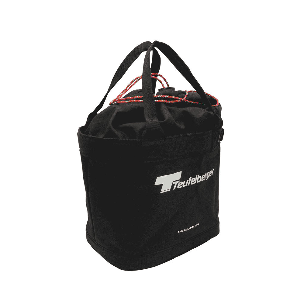 Bucket Mule von Teufelberger, schwarze runde Tasche mit zwei schwarzen Tragegriffen und rotem Kordelverschluss, Vorderseite mit weißem Teufelberger-Logo und Schriftzug "AMBASSADOR LINE"