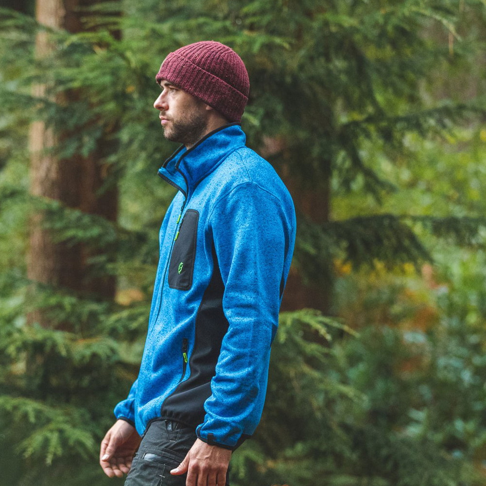 Mann trägt blaue Kudu Plus Fleecejacke mit schwarzer Brusttasche in einem Wald