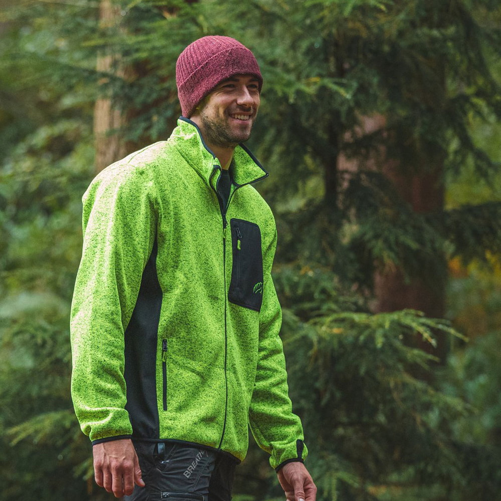 Mann trägt grüne Kudu Plus Fleecejacke mit schwarzer Brusttasche in einem Wald