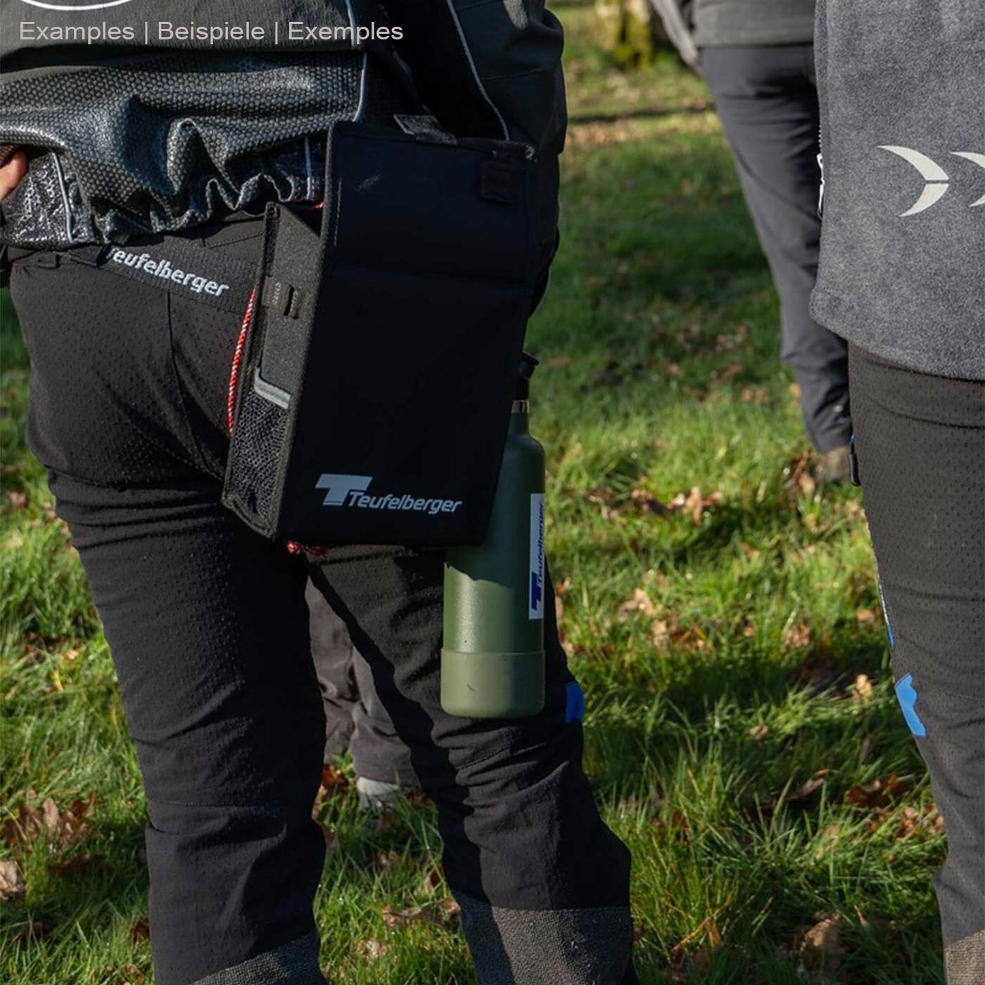 Mini Mule von Teufelberger, an der Hüfte einer Person befestigt, schwarze Tasche mit Teufelberger-Logo, daneben eine grüne Flasche mit Teufelberger-Logo