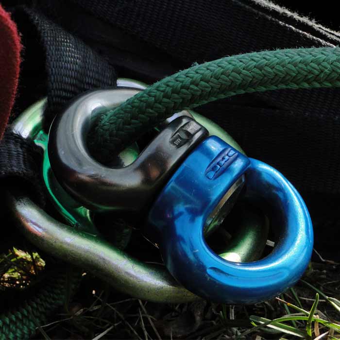 Axis Swivel S, drehbarer Verbindungspunkt in blau und schwarz verbunden mit grünem Seil und anderem Metallzubehör auf Grasboden