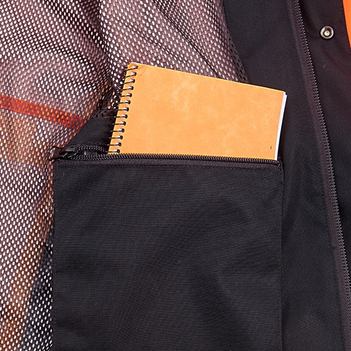 Innenseite der Keiu Regenjacke mit schwarzer Reißverschlusstasche, in der ein orangefarbenes Notizbuch steckt