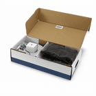 Geöffnete Verpackung des Husqvarna Automower Installations-Kit S mit sichtbaren Kabelrollen, kleinen Plastiktüten mit Zubehör und weiteren Komponenten im Karton.
