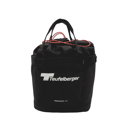 Bucket Mule von Teufelberger, schwarze runde Tasche mit zwei schwarzen Tragegriffen und rotem Kordelverschluss, Vorderseite mit weißem Teufelberger-Logo und Schriftzug "AMBASSADOR LINE"