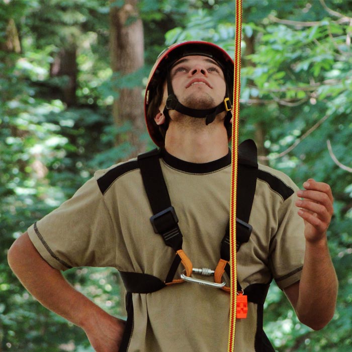 Ein Mann trägt einen roten Helm und einen Klettergurt, an dem ein rot-gelb geflochtenes Seil befestigt ist, Produktname XP-e Highlight
