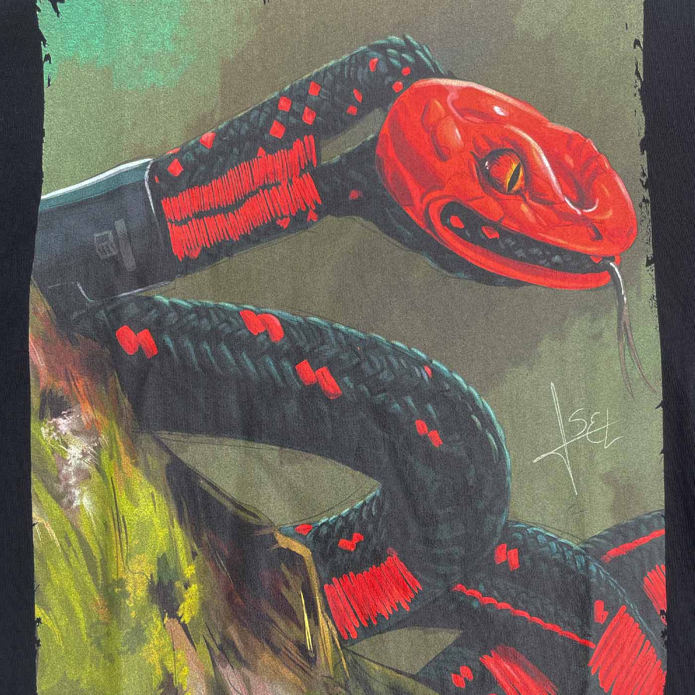 Nahaufnahme des farbigen Schlangendesigns auf dem schwarzen ART Snake Shirt mit roten und schwarzen Details und einer grünen Hintergrundfläche