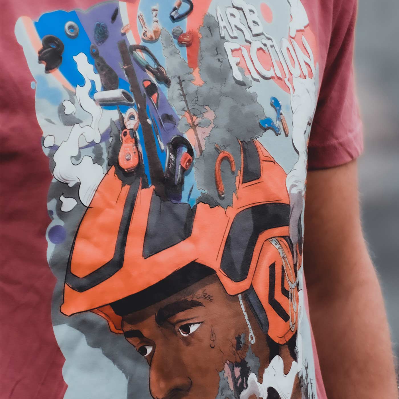 Nahaufnahme eines roten T-Shirts mit demselben bunten Aufdruck eines Mannes mit orangefarbenem Helm und dem Text "ARB FICTION", Produktname Mind Fuck