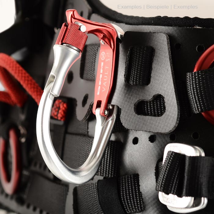 Vault Lock Karabiner in Silber und Rot, befestigt an einem schwarzen Gurtsystem mit roten und schwarzen Schlaufen und Metallteilen