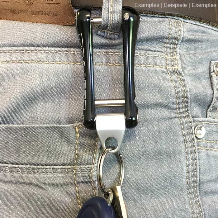 Trapeze Auge aus Metall mit der Gravur ART, befestigt an einem schwarzen Kunststofftrapez, das an einem Gürtel mit Schlüsselring und Schlüsseln hängt