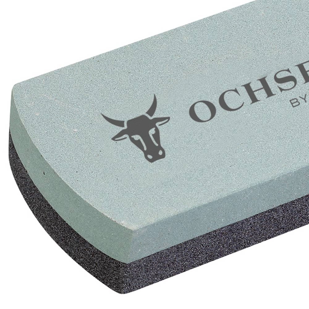 Nahaufnahme des Silizium-Carbid Schleifsteins, Fokus auf die hellgraue Oberfläche mit dem Schriftzug "OCHSENKOPF BY GEDORE" und dem Stierkopf-Logo
