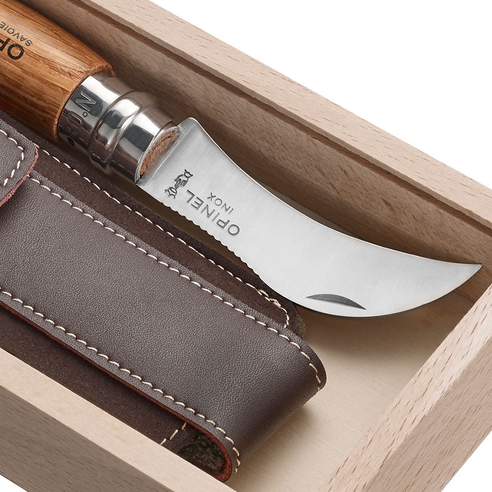 Nahaufnahme des gebogenen Messers mit der Gravur "OPINEL INOX" und des Lederetuis in der hellen Holzschachtel