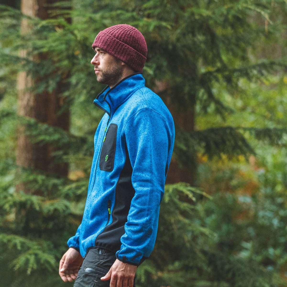Mann trägt blaue Kudu Plus Fleecejacke mit schwarzer Brusttasche in einem Wald