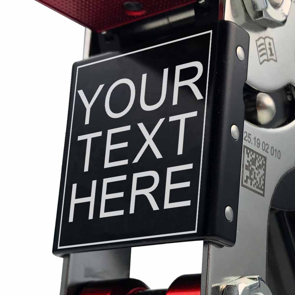 Nahaufnahme der Texttafel mit der Aufschrift "YOUR TEXT HERE" am SpiderJack 3 – Laser Text Klettergerät, sichtbare Schrauben und QR-Code am silbernen Rahmen