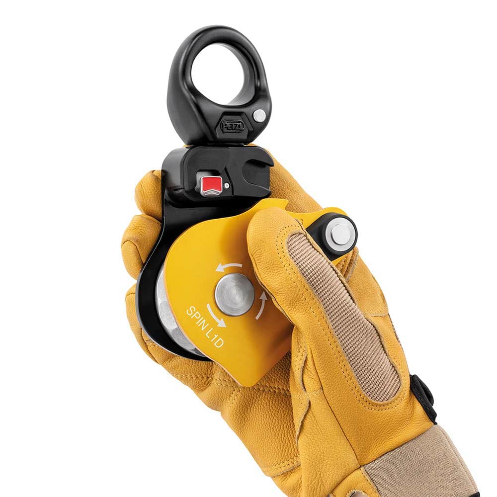 Petzl Spin L1D Seilrolle mit Handschuh an einer Hand, die die Rolle hält