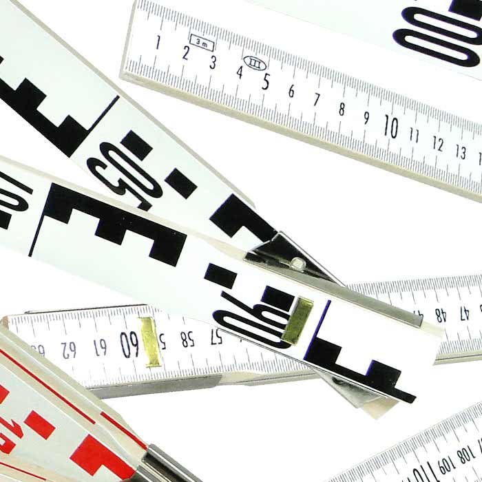 Geometer-Maßstab mit weißen Segmenten, schwarzen und roten Zahlen und Markierungen, nahaufnahme von Gelenken und Skalen