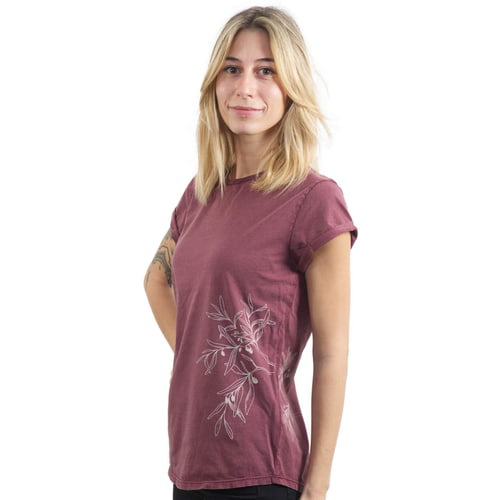 Eine Frau trägt ein bordeauxrotes T-Shirt "Olive Branch" mit weißem Olivenzweig-Motiv an der Seite und hat die Hände hinter dem Rücken.