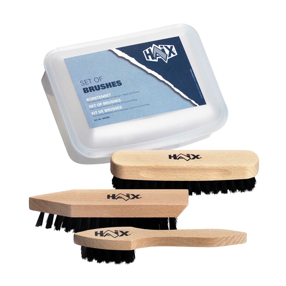 Bürsten Set von HAIX mit drei Holzbürsten unterschiedlicher Form und schwarzem Borstenbesatz sowie einer transparenten Kunststoffbox mit blauem Etikett und HAIX-Logo