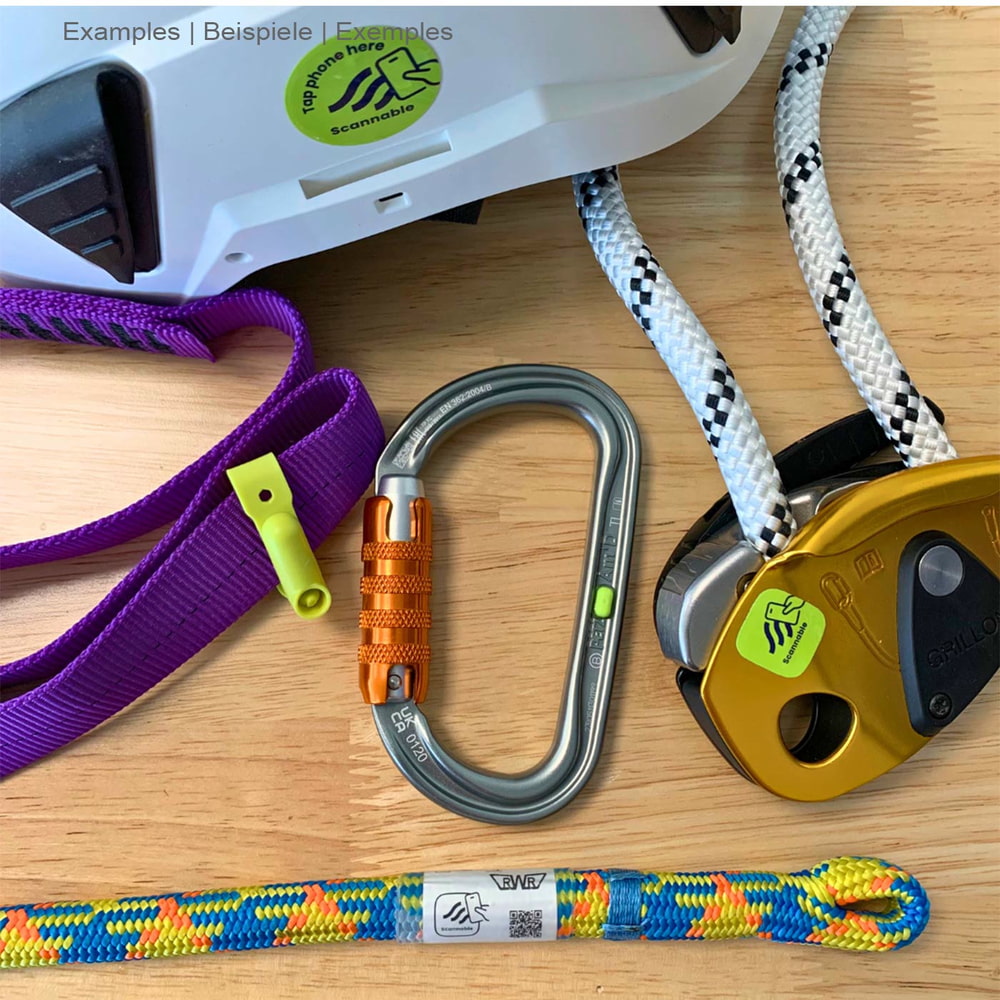 Climber Pack NFC Tag mit Kletterausrüstung wie Karabiner, Seilen und Gurtband, teilweise mit grünen Scannable-Aufklebern beklebt, auf einem Holztisch