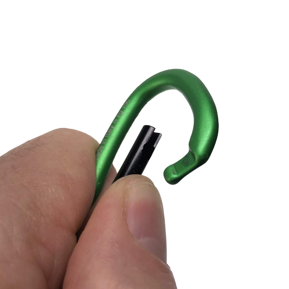 Grüner Karabinerhaken Big Mini mit schwarzem Verschlussmechanismus, gehalten von einer Hand vor weißem Hintergrund